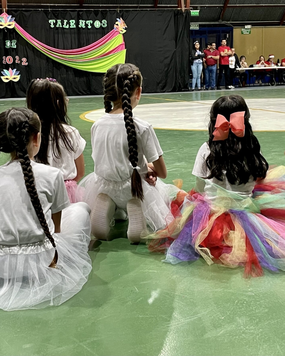 Young dancers at a local school watching other performers while awaiting their turn to perform in San Isidro, Costa Rica as photographed by Rhonda Jesckey