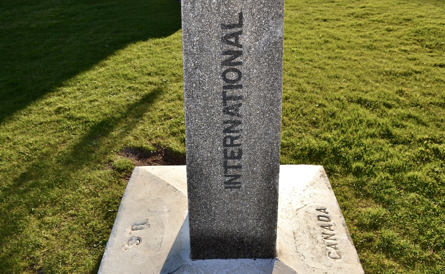 International border marker made of stone that says US and Canada on either side. Photography by Rhonda Jesckey