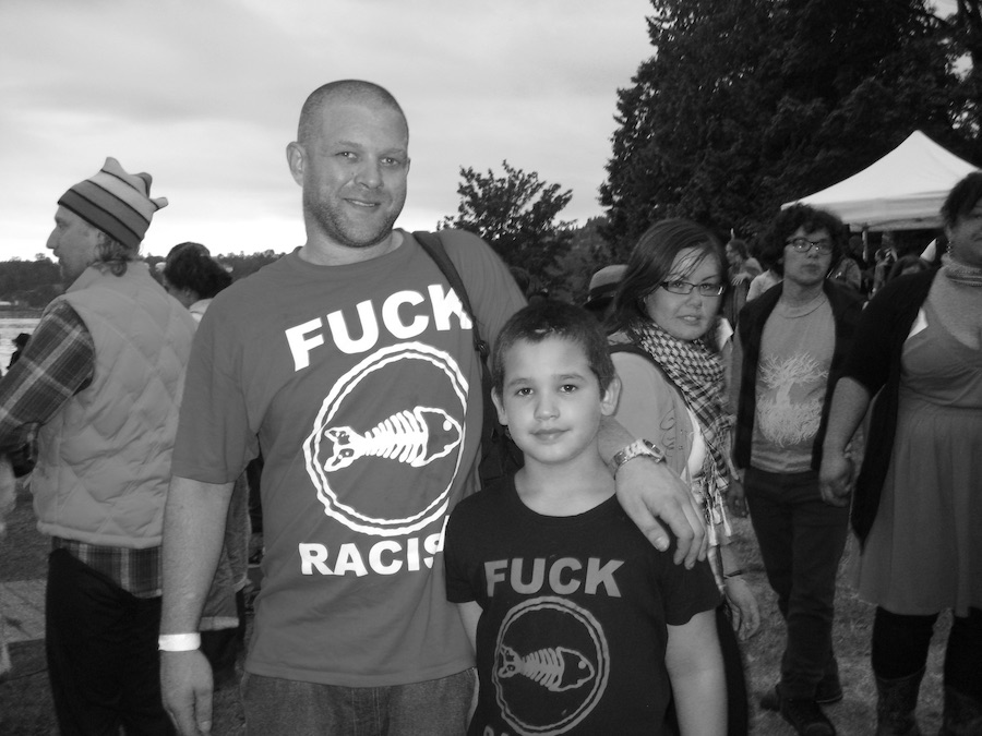 Photo of a man and a child with T-shirts that say Fuck Racism (from the band Fishbone). Photography by Rhonda Jesckey.
