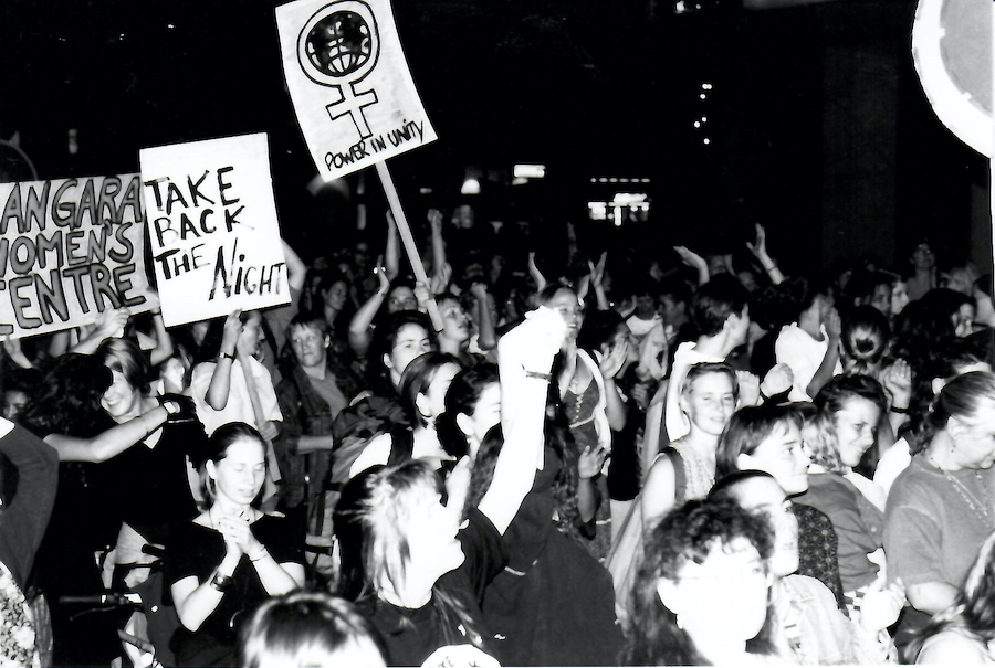 A big crowd of women fill Robson Street in Vancouver carrying signs that say - Take Back the Night, Power in Unity and Langara Women's Centre. Photography by Rhonda Jesckey.